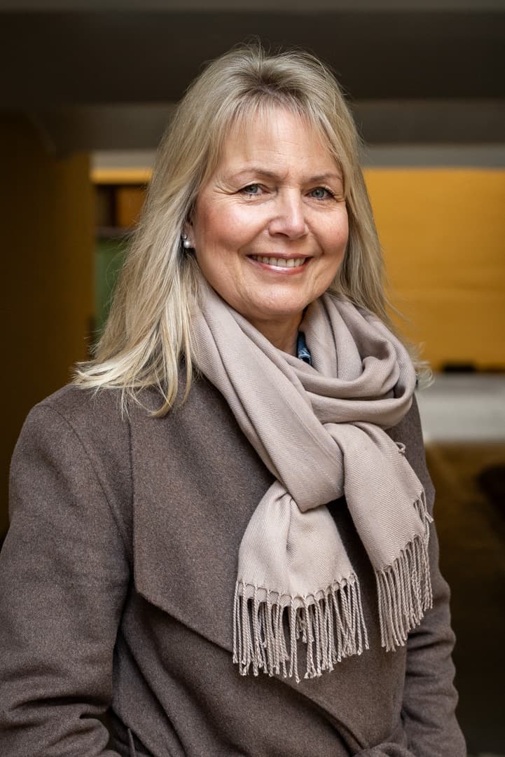 Ine ser inn i kameraet og smiler. Har på seg jakke og skjerf.