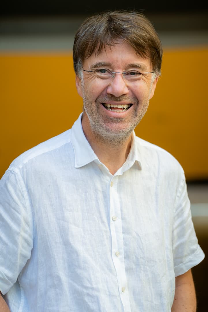 Trygve har på hvit skjorte og ser inn i kameraet og smiler.